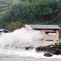 巨浪衝向鹿兒島縣岸邊一列房屋。 美聯社圖片