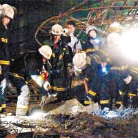 消防員搜救被埋在廢墟下的工人。