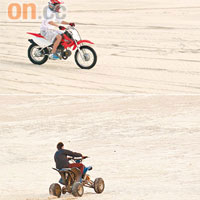 在沙漠上看見越野電單車和四驅車在馳騁。