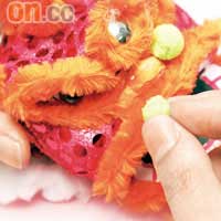 在獅頭貼上膠眼珠，以及在眉目、嘴巴貼上毛絨線，而鼻子兩端則貼上毛絨球。