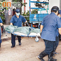 仵工將女死者屍體舁走。