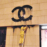 法國藝術家Zevs用梯爬上外牆「溶解」Chanel嘜頭。	讀者提供圖片