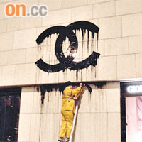 身穿黃色雨衣的Zevs當晚在GIORGIO ARMANI旗艦店外牆「溶解」CHANEL商標。 資料圖片