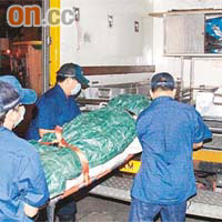 仵工將死者屍體搬往殮房。