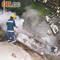 消防員向不斷冒煙的汽車灌救。