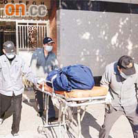 仵工將女死者屍體舁走。