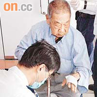 救護員為受傷老翁包紮手部傷口。