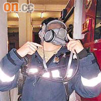 一名疑似「消防員」示範如何佩戴煙帽口罩工具。