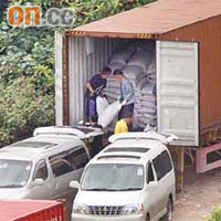 兩輛七人車在沙頭角貨場上貨，工人不斷將多包疑似白色麵粉袋包裹的貨物搬上七人車。