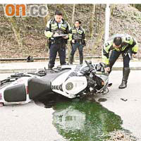 警員檢查翻倒路中的損毀電單車。朱偉坤攝