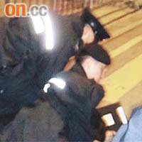 一名示威者被兩名警員按在地上。