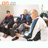 保健員阿輝（右）上門為伍伯（中）進行復康運動治療，舒展腳部。