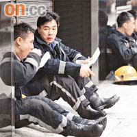 筋疲力盡的消防員坐在街上吃飯盒充飢。