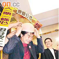 梁國雄戴上光頭頭套及打着傘報名參選，諷刺中央及港府打壓「公投」的行為「無法無天」。