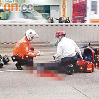 頭部重創鐵騎士倒臥車旁，救護員在場搶救。	讀者提供