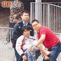 受傷鐵騎士獲救後一臉驚惶，其中一名救人英雄鄧少鴻（右）幫手抬送傷者。