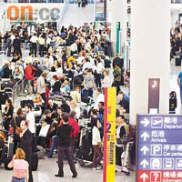 數以百計滯留本港的旅客蜂擁到機場撲機位，幾近逼爆離境大堂。