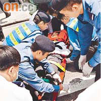 救護員搶救喇沙男生時，途人在旁打傘。