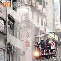 消防員升起雲梯向畫室火場灌救。