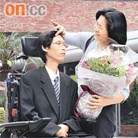 劉曉鋒母親一手抱着兒子所送鮮花，一手替兒子整理頭髮。