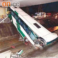 失事旅遊巴車頭撞扁,擱在明渠上。