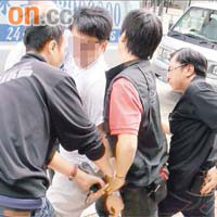 探員取走疑犯相機及扣上手銬。