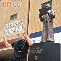 有示威者昨日到浸大孫中山銅像前，舉牌向中文大學抗議。