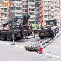 逾百支鋼筋由貨車（右）跣落地，需召吊車清理。