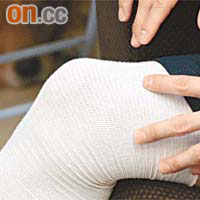 手術後的左膝綁上厚厚綳帶，右膝則套上護膝。
