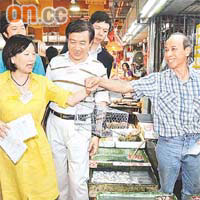 鼠王芬喺北河街街市派《滅鼠天書》，有商販向佢出示自備嘅老鼠籠。