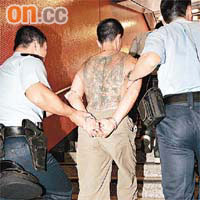 背部有紋身的疑犯被鎖上手銬拘捕。