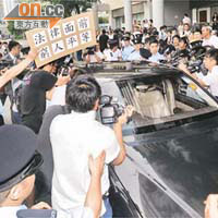 包致金姪女乘私家車離開時場面混亂，有市民更舉標語抗議。