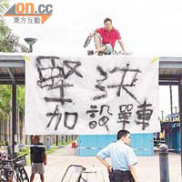男子爬上行人路的簷篷，掛起抗議橫額要求加設單車泊位。