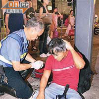 傷者坐在電車站由救護員急救。