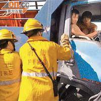 運魚車司機受傷被困,跟車工人在旁安慰,消防員設法營救。