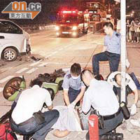 客貨車與電單車相撞後，傷者躺在路中急救。