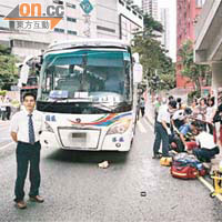 救護員為女傷者急救，旅遊巴司機（左）在現場助查。