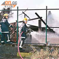 消防員向起火鐵皮屋灌救。