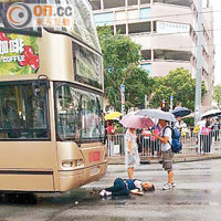 老婦捱巴士撞 途人打傘擋雨